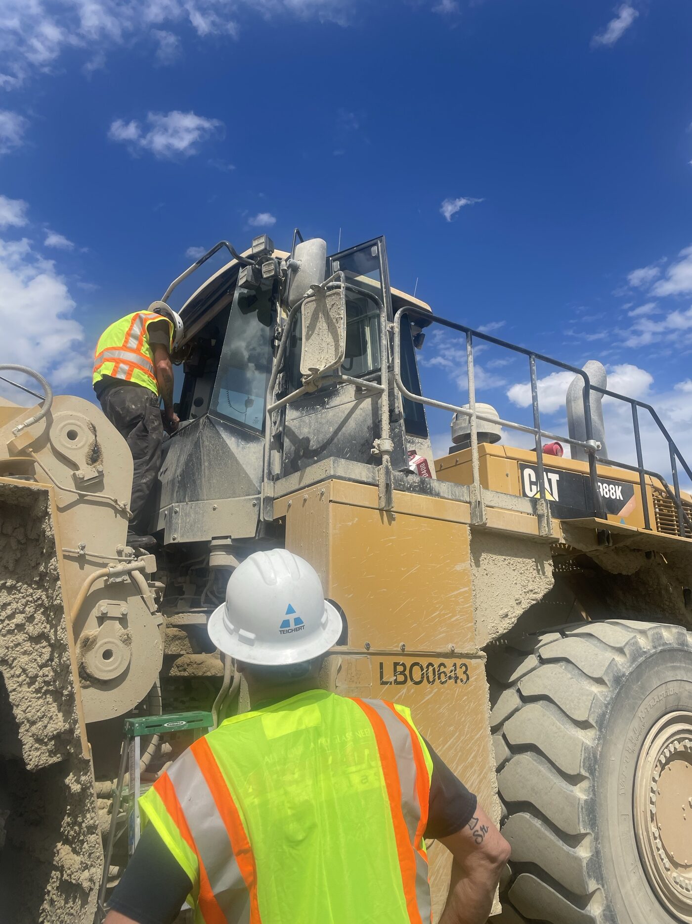 Technicians replacing cab glass on a Cat 988K wheel loader