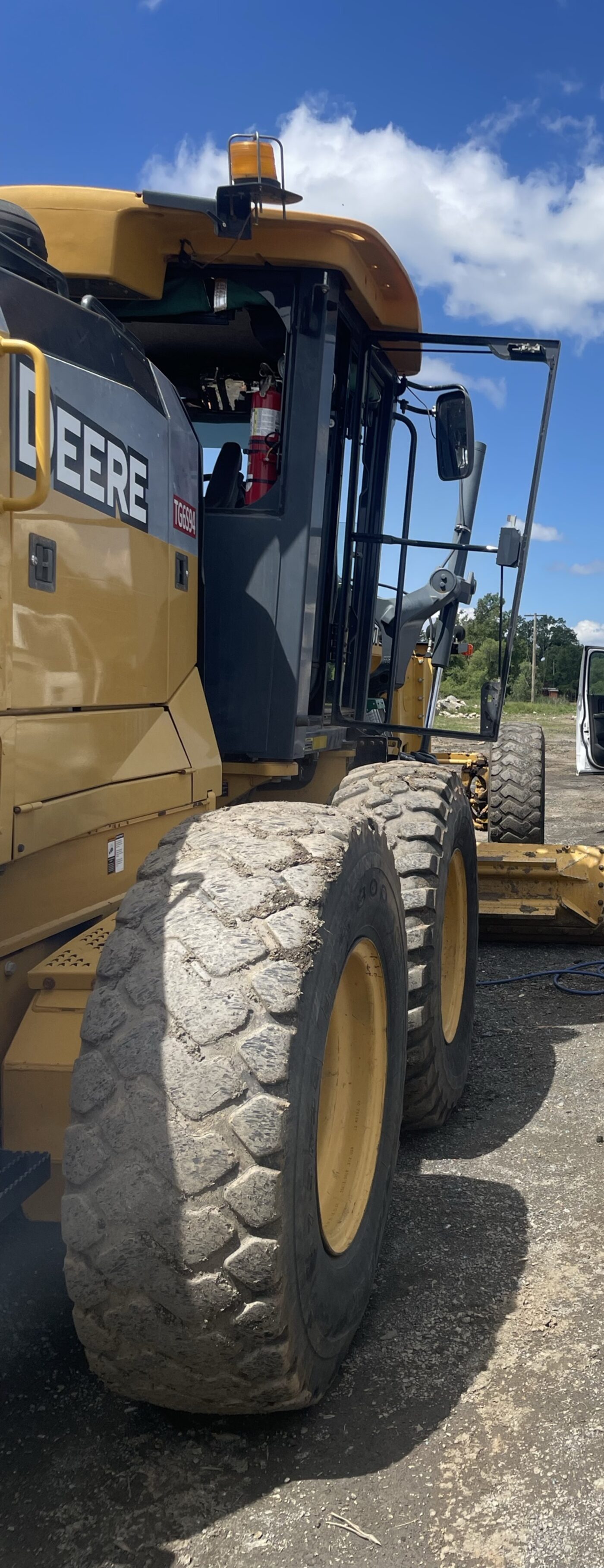 A John Deere motor grader with the cab door glass removed for replacement