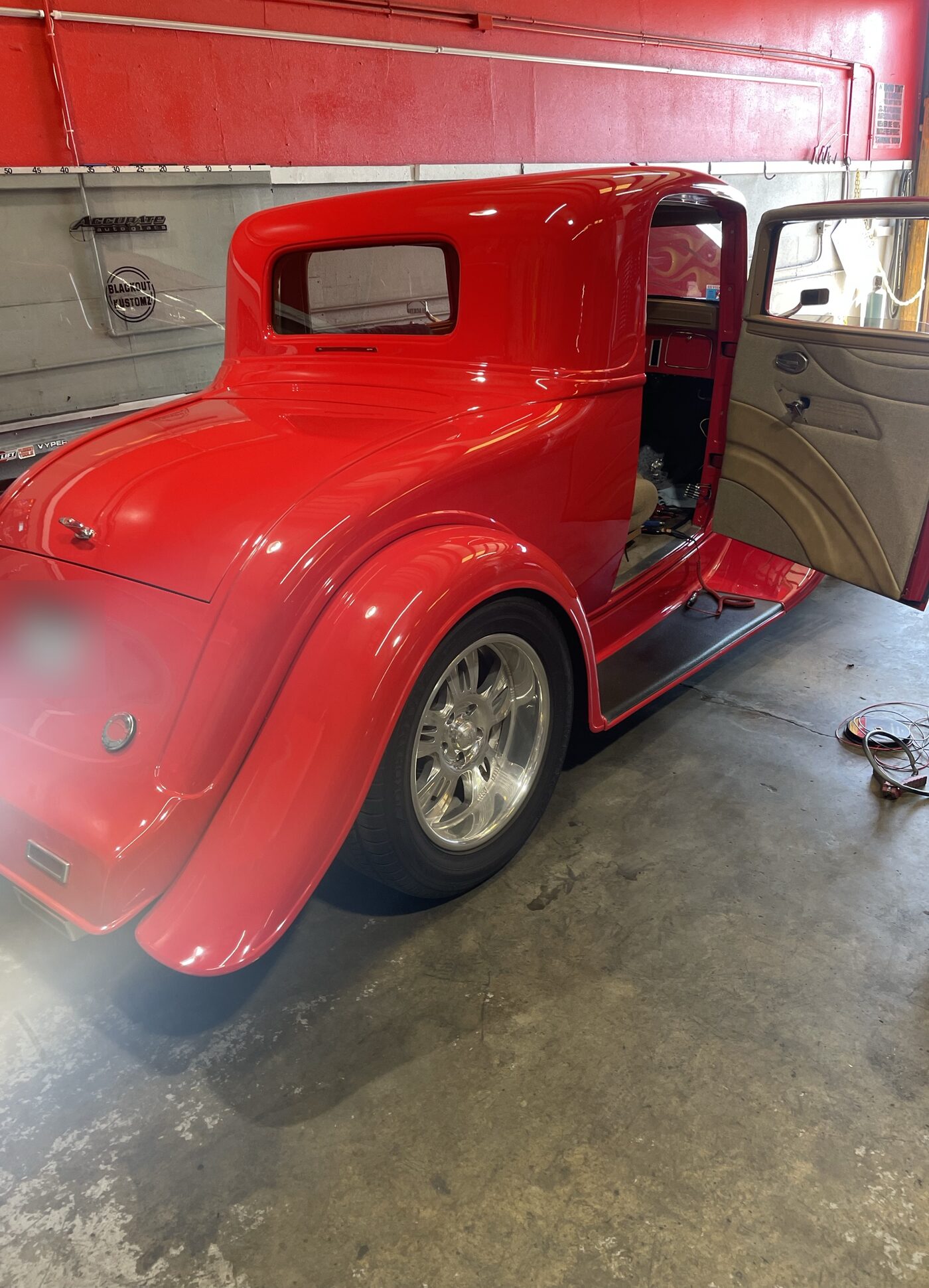 A red 1930s hot rod coupe in the shop for glass