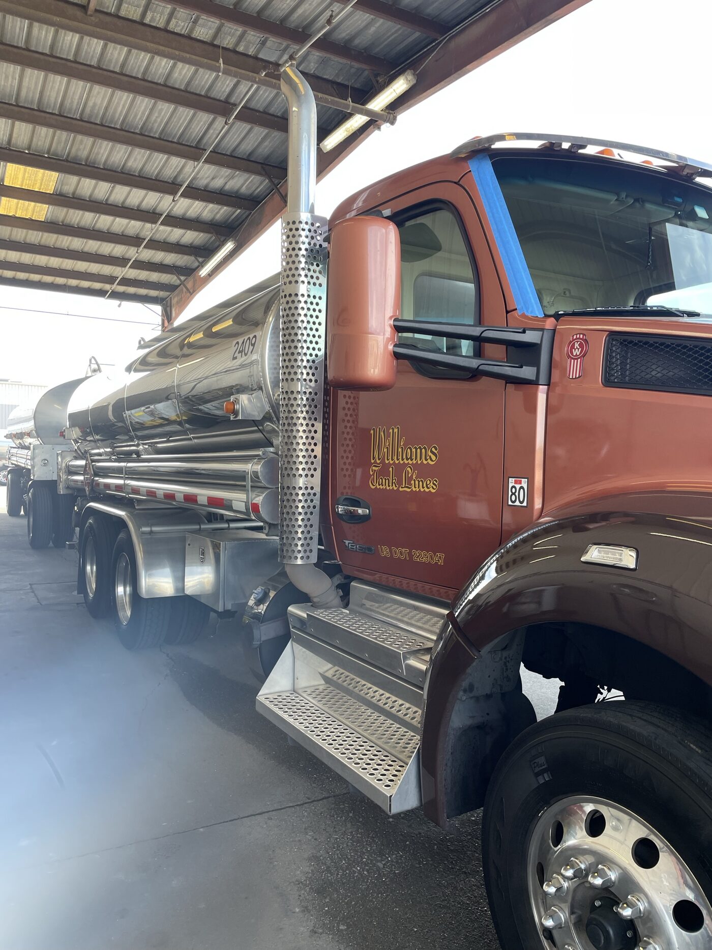 A Kenworth tanker truck with a freshly installed windshield, still taped