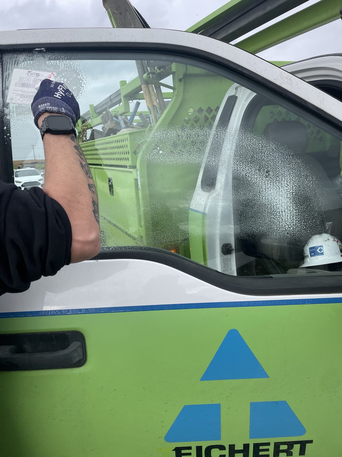 A technician cleaning newly installed glass on a work truck
