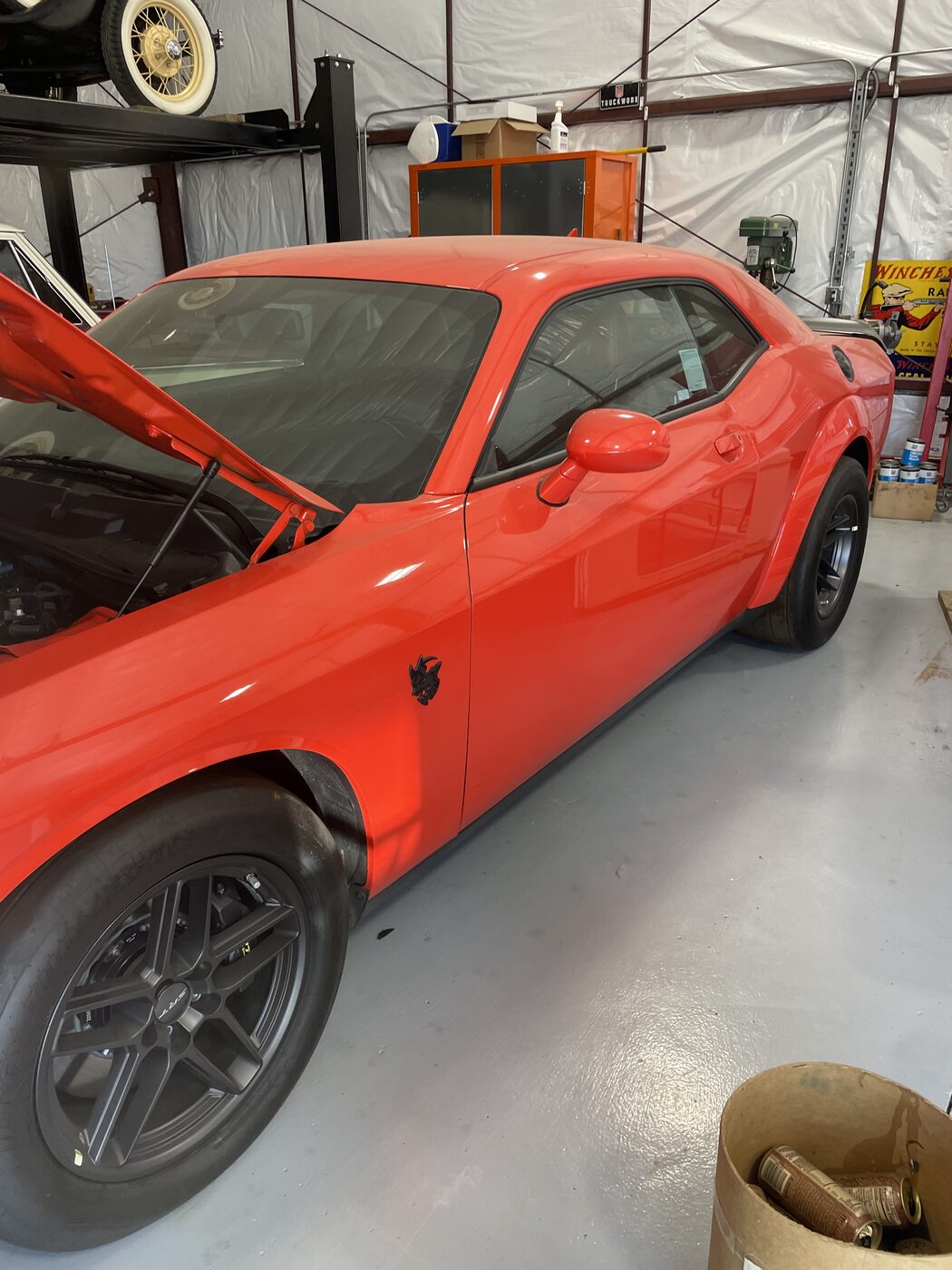 An orange Dodge Challenger in the shop for glass
