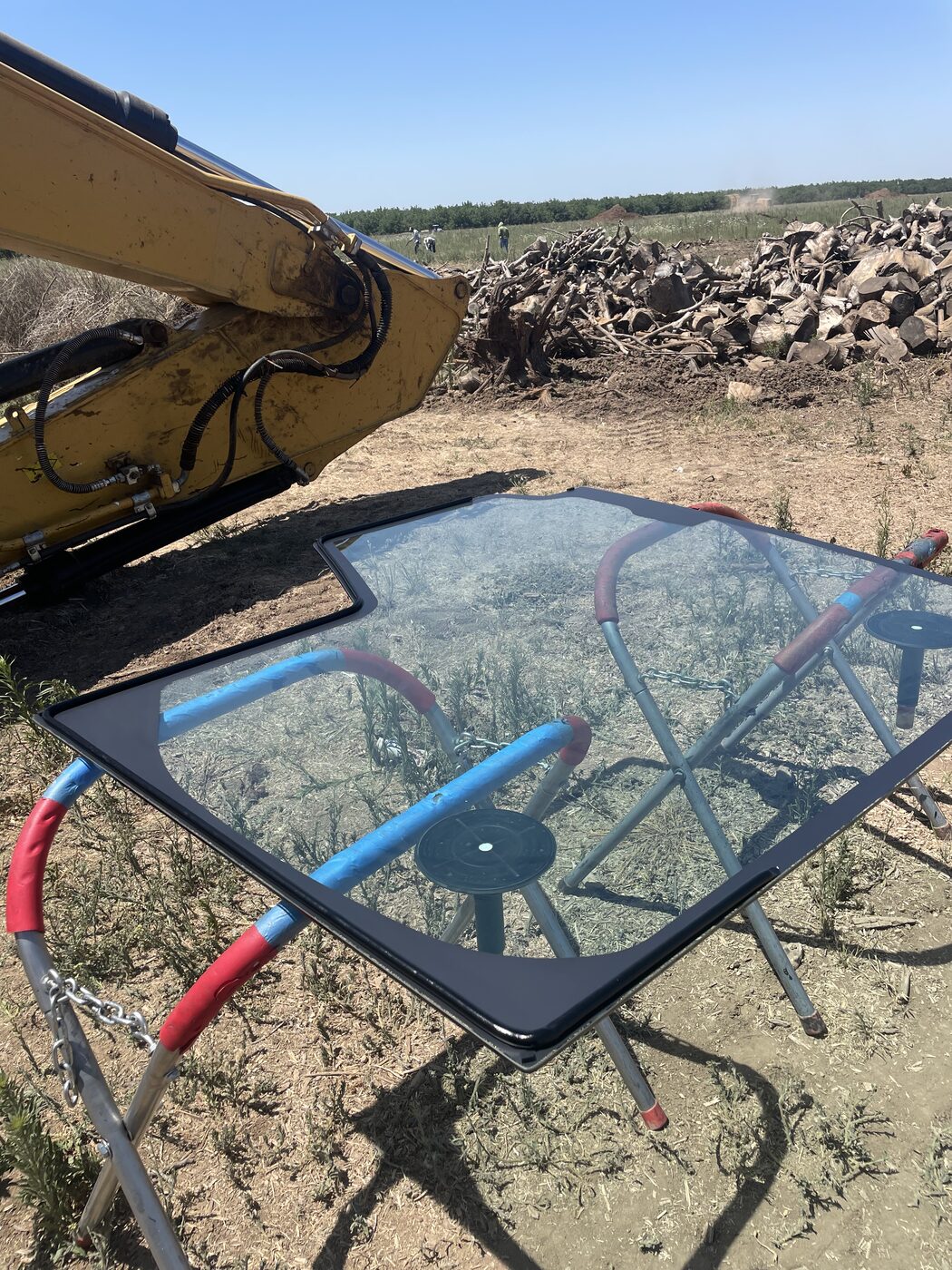An excavator windshield removed and set on the ground for replacement