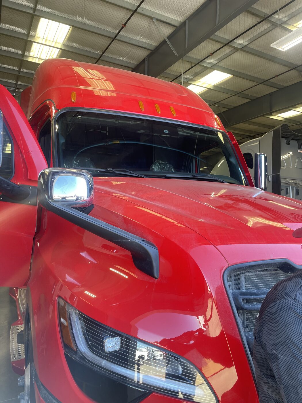 A red semi truck in the shop for a windshield